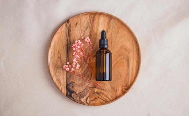 Small aromatherapy eyedropper bottle on wooden display plate.